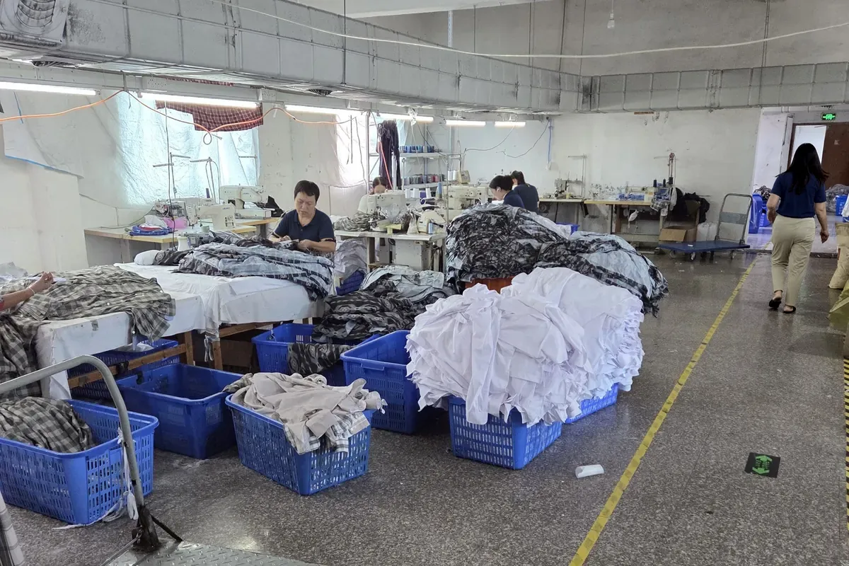 Bundled panels in bins beside sewing machines on a production floor in China