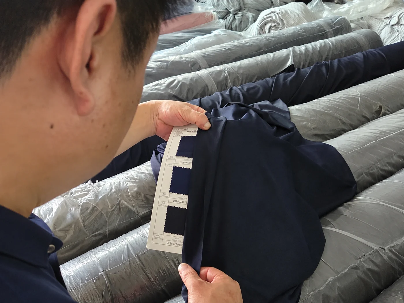 Fabric held against the approved color card at the roll racks before cutting